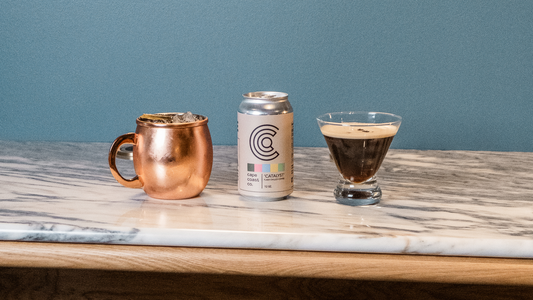 Copper mug, Catalyst coffee can, and coffee cocktail on marble counter with blue background